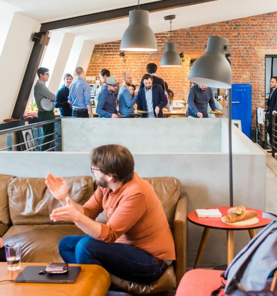 man in orange dress shirt talking and sitting in front of woman on brown sofa