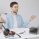 Man practising mindfulness meditation at his desk with a laptop, notebook, and headphones in a home office setting