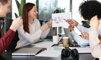 Team meeting in modern office with diverse colleagues discussing colourful pie chart and strategies at conference table