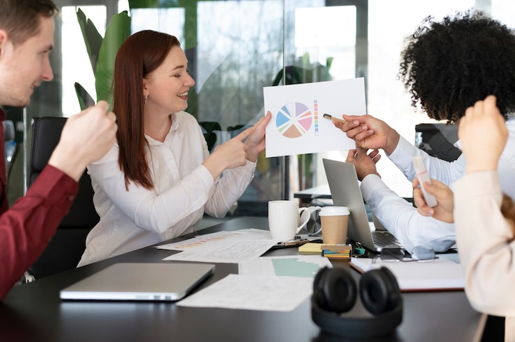 Team meeting in modern office with diverse colleagues discussing colourful pie chart and strategies at conference table