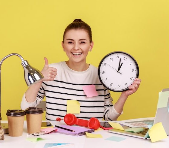 Person smiling and holding a clock, surrounded by sticky notes, coffee cups, and office items on a yellow background