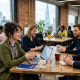 Team collaborating in a modern office with laptops and city skyline view in London